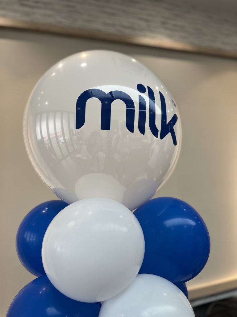 A group of blue and white balloons with the word MILK pasted on one balloon