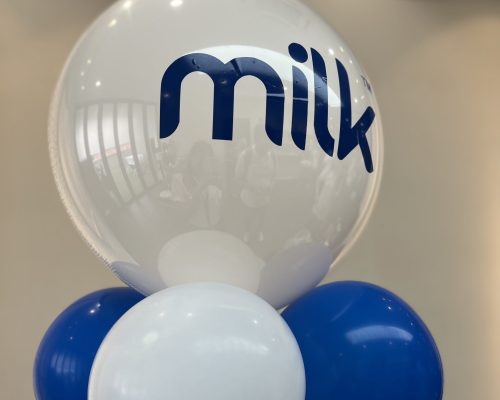 A group of blue and white balloons with the word MILK pasted on one balloon