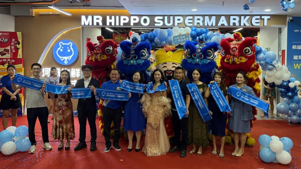 Attendees holding blue banners during the launch event for Mr. Hippo Supermarket.
