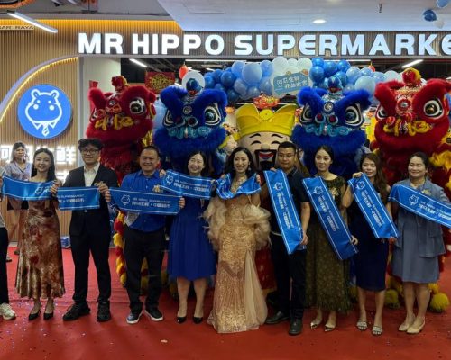 Attendees holding blue banners during the launch event for Mr. Hippo Supermarket.