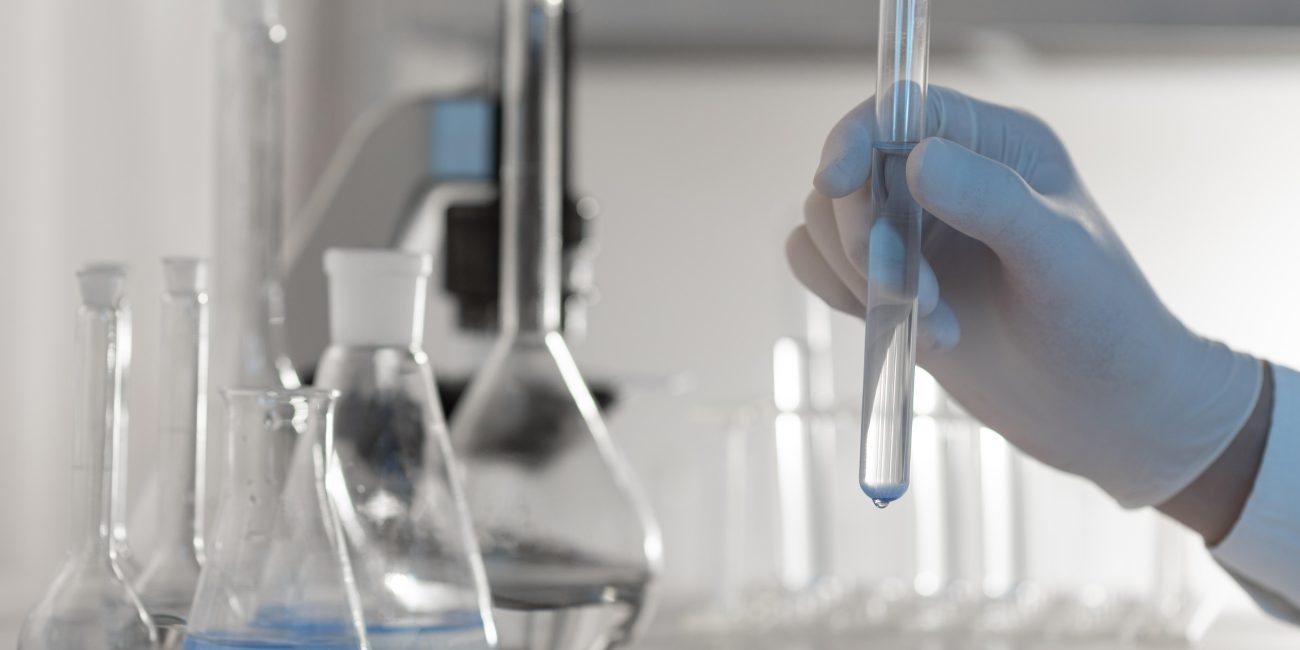 A close up hand holding tube with solution