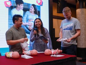 Expectant fathers doing a diaper change challenge with dolls